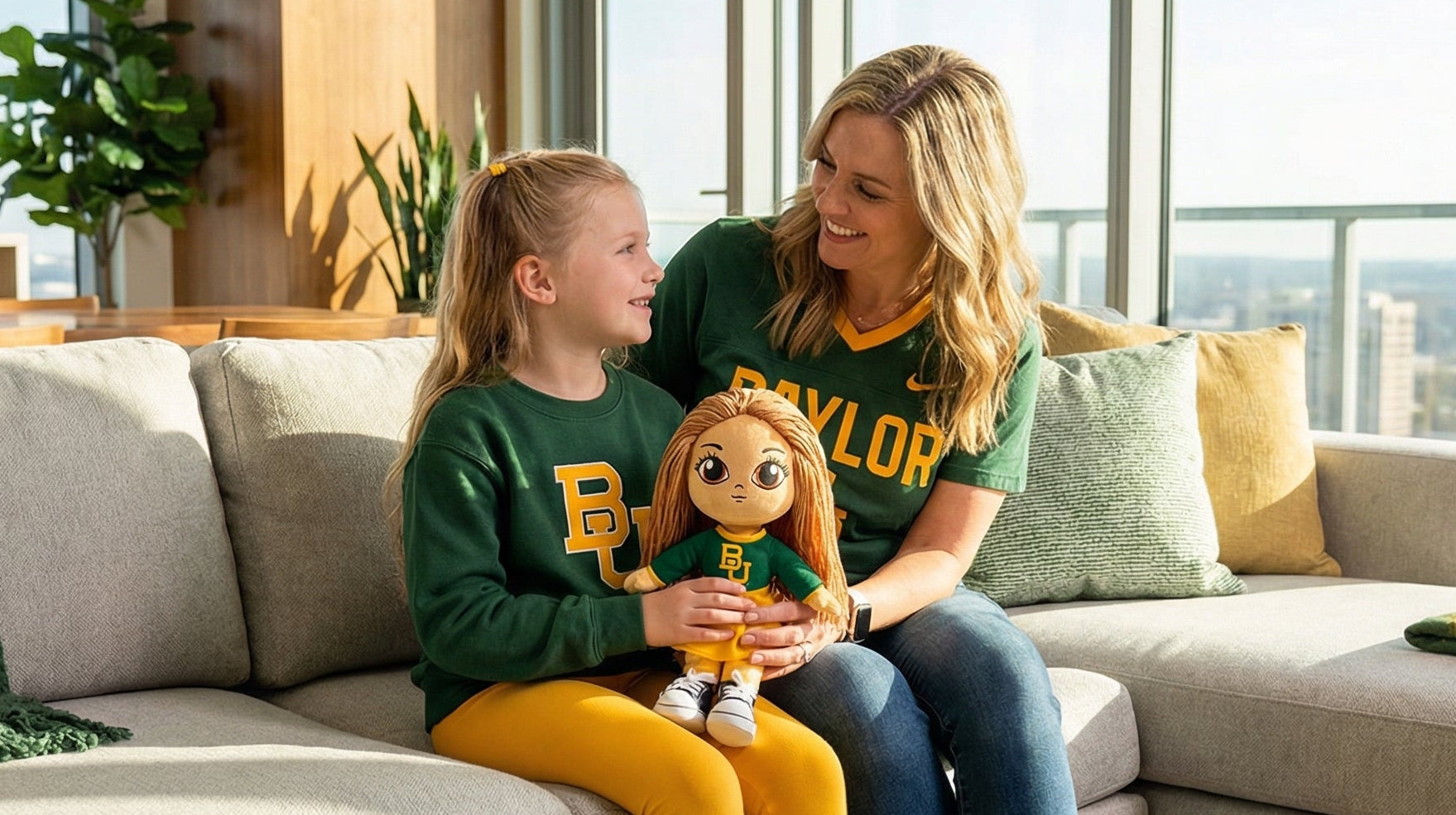 Woman and child sitting on a couch holding a toy, with a cityscape view through large windows.