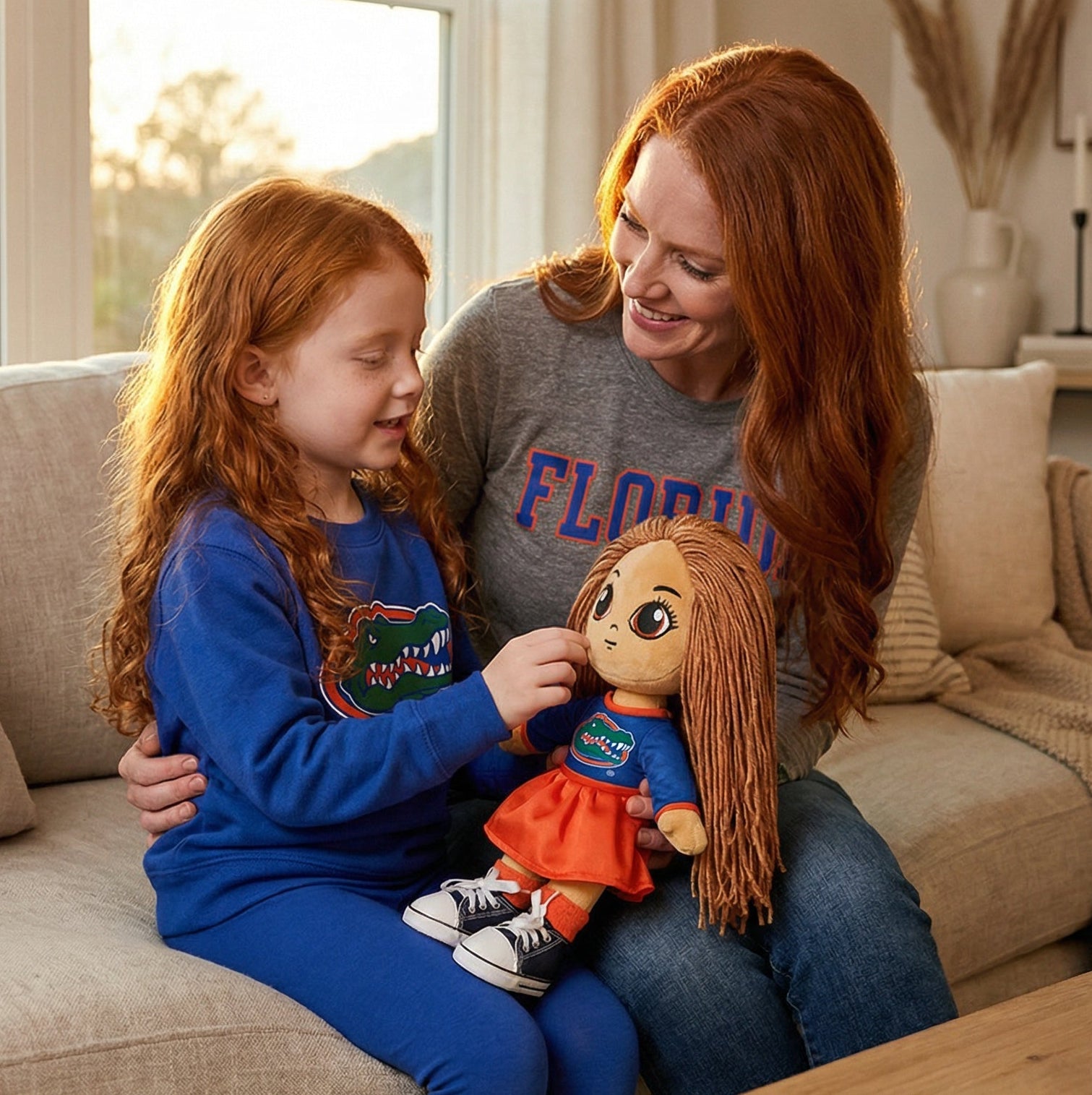 Woman and child sitting on a couch holding a doll in a cozy living room.