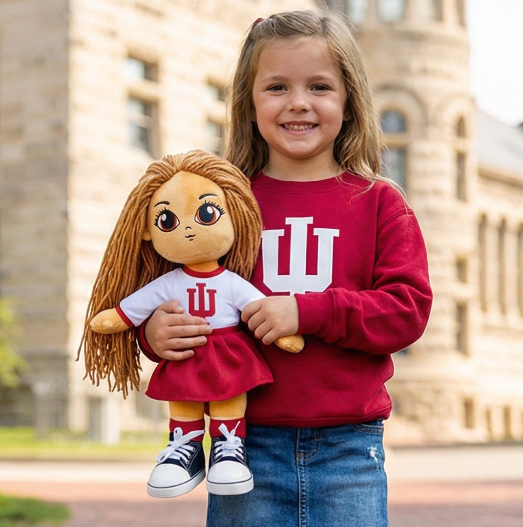 Young girl holding a doll with Indiana University clothing in front of a historic building.