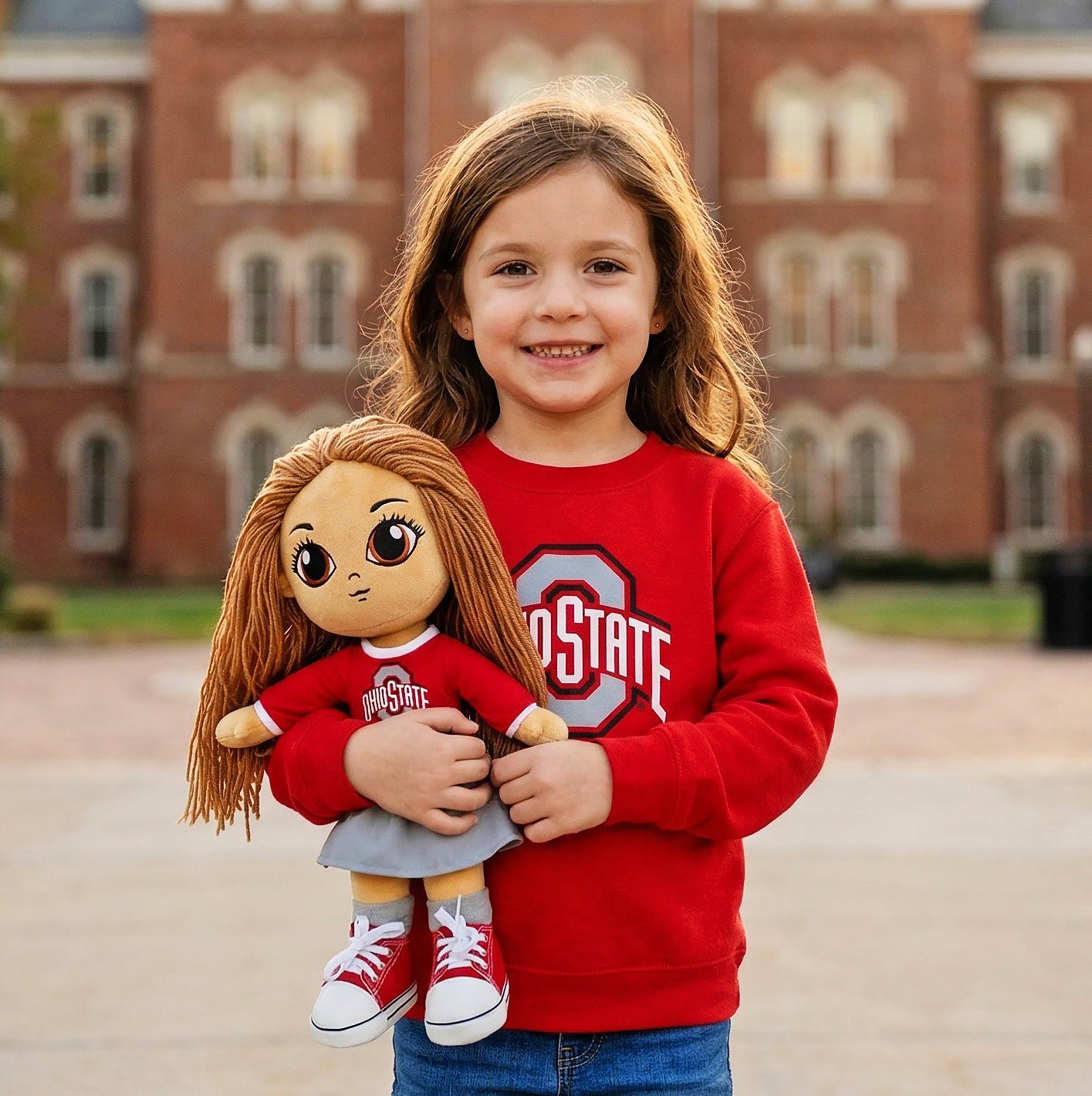 Child holding a doll with a building in the background
