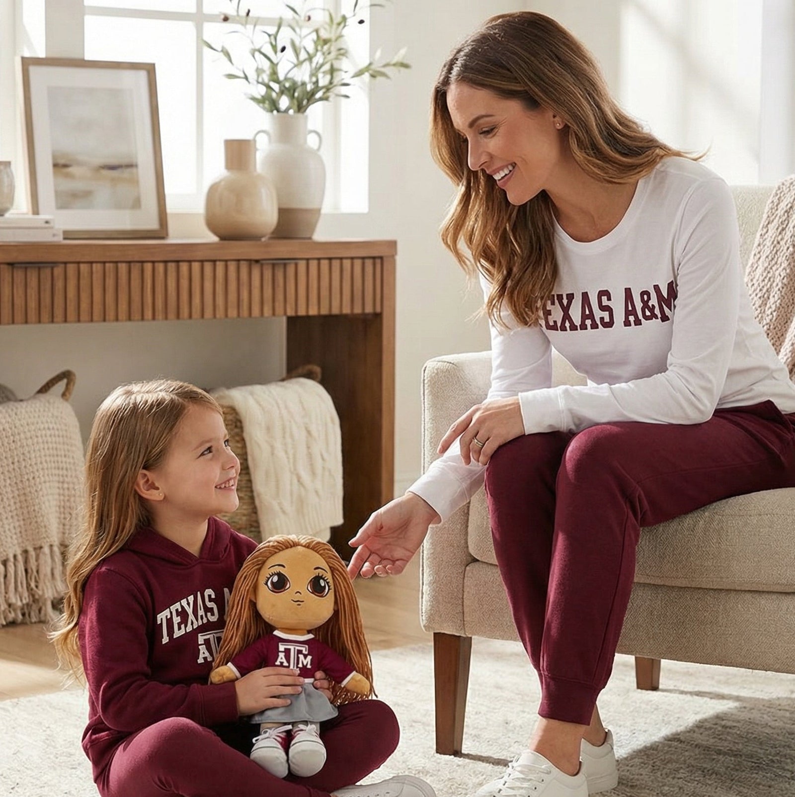 Woman and child sitting on a rug in a living room, both wearing Texas A&M clothing.